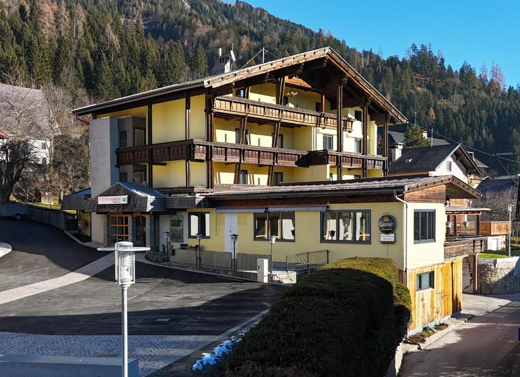 a large yellow building with a mountain in the background at Frühstückspension Irschen in Irschen