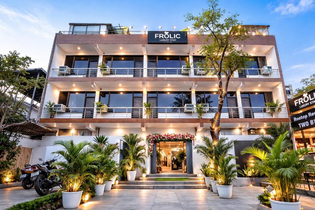 a hotel with a facade with palm trees in front at Frolic Hotel Near Sec 52 Noida Metro Station in Noida