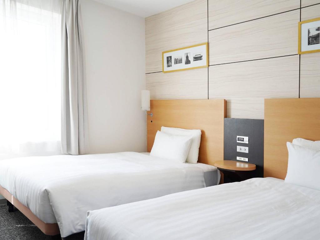 a hotel room with two beds and a window at Comfort Hotel Tokyo Higashi Nihombashi in Tokyo
