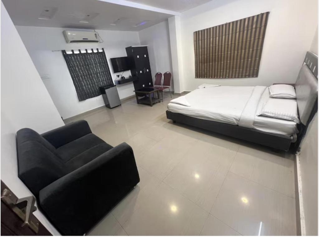 a bedroom with a bed and a couch and a chair at Highway Grand Residency in Hyderabad