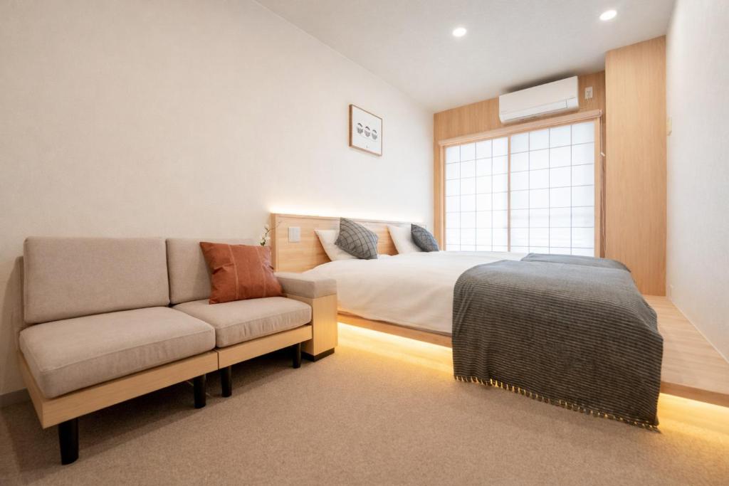 a bedroom with a bed and a couch and a window at b&黒門3号店 in Osaka