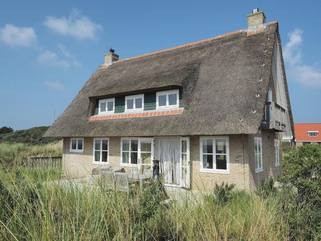 una antigua casa de ladrillo con techo de paja en Beautiful villa on Terschelling in the dunes 150 meters away, en Midsland aan Zee