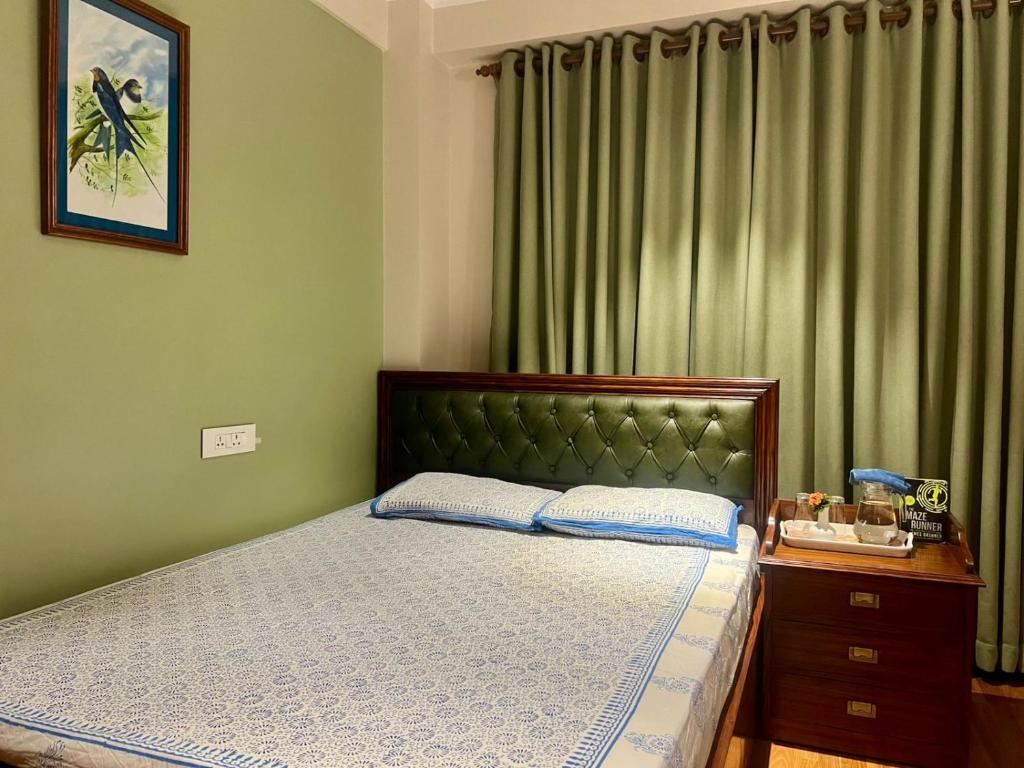 a bedroom with a bed with green walls and curtains at Shivalaya Suites in Pātan