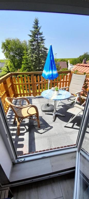 a patio with a table and a blue umbrella at Haus Seemöwe Obergeschoss in Wittmund