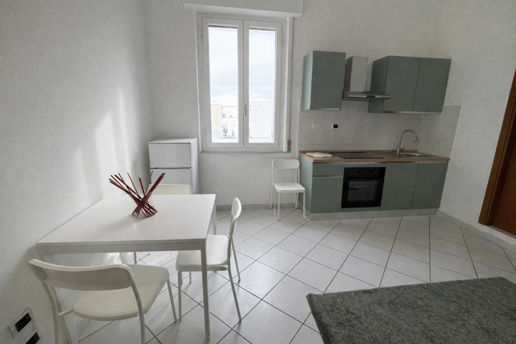 a kitchen with a white table and chairs in a room at La casa di Lollo in Piombino