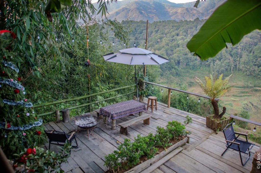 a wooden deck with a bench and an umbrella at Bản Sù - Homestay in Sapa