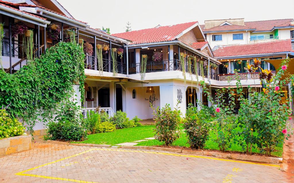 a large white house with a yard with flowers at Trisan Resident Hotel in Nairobi