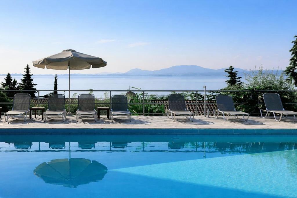 a group of chairs and an umbrella next to a swimming pool at Hotel Barbati - Seaside Getaways with Pool in Barbati