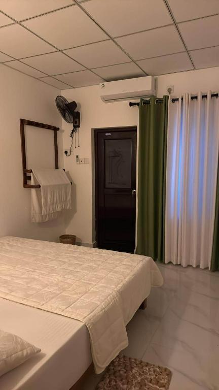 a bedroom with a bed and a green curtain at Wilpattu Leisure Villa in Pahala Maragahawewa