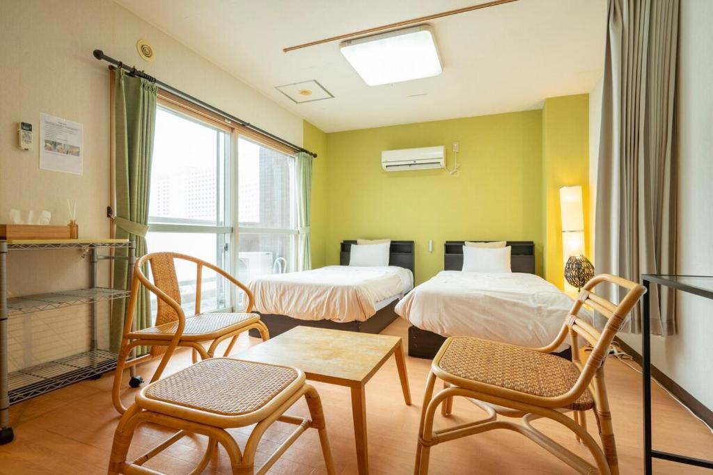 a room with two beds and two chairs and a table at Fewdays Condominium608 in Sapporo