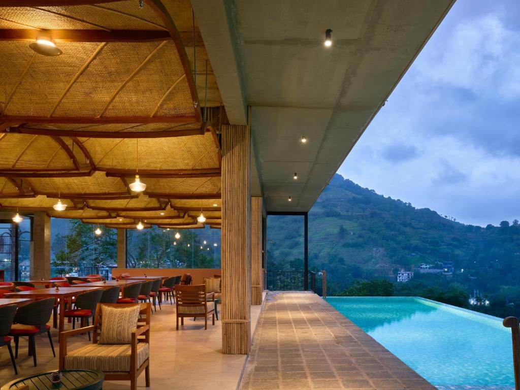 a restaurant with a pool and tables and chairs at Te Dalu Resort & Spa - A Luxury Sanctuary in Ella in Ella