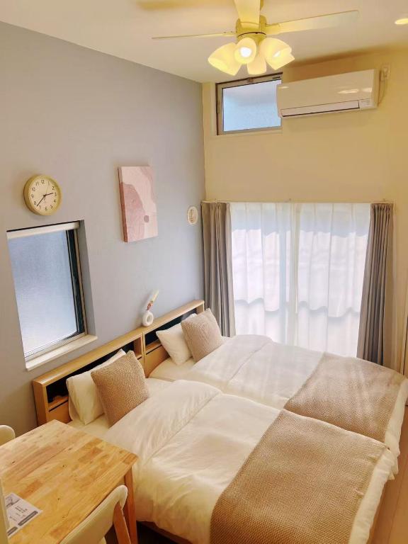 a bedroom with two beds and a table and a clock at Le Amo吉塚 in Fukuoka
