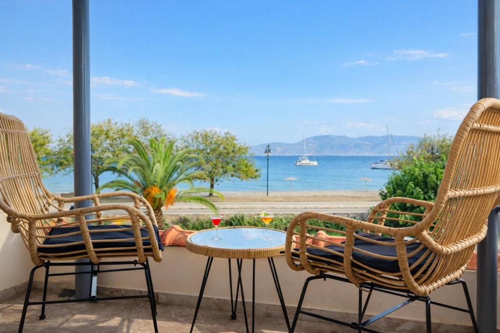 a patio with two chairs and a table and a view of the ocean at Beachfront Villa Psani - Escape with Garden in Nafpaktos
