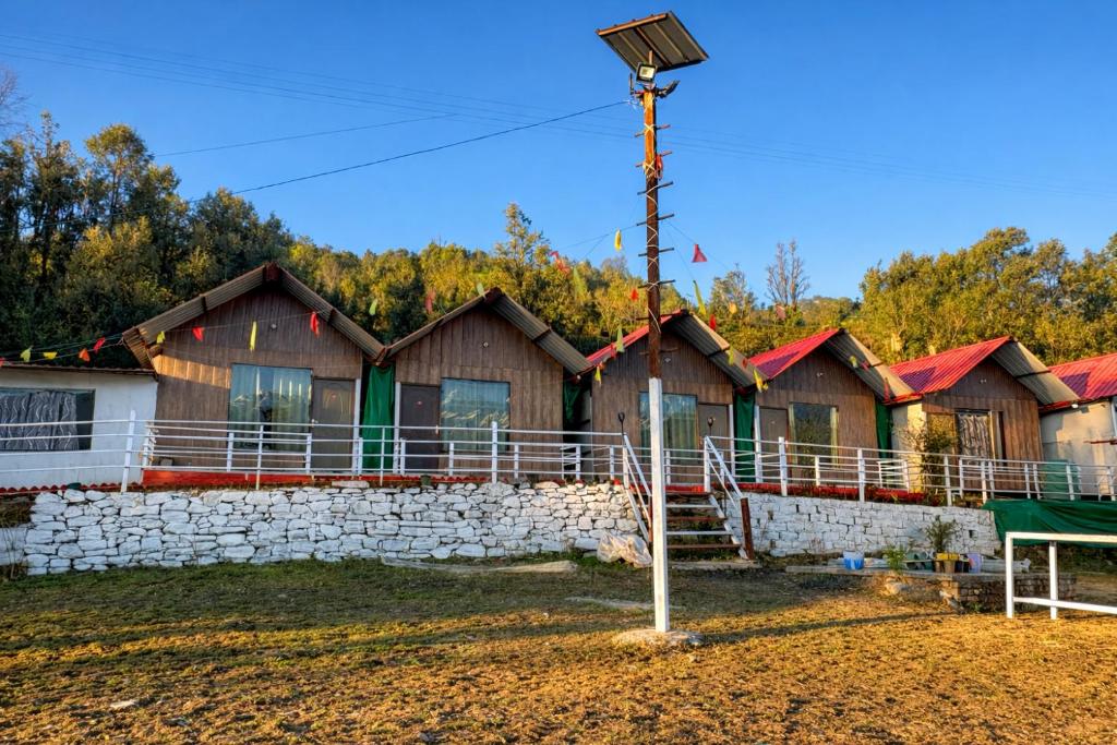 a row of wooden houses with a stone wall at Kedar Avnita Resort in Gupta Kāshi