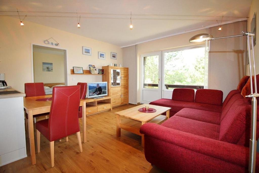 a living room with a red couch and a table at Golfresidenz B 109 in Grömitz