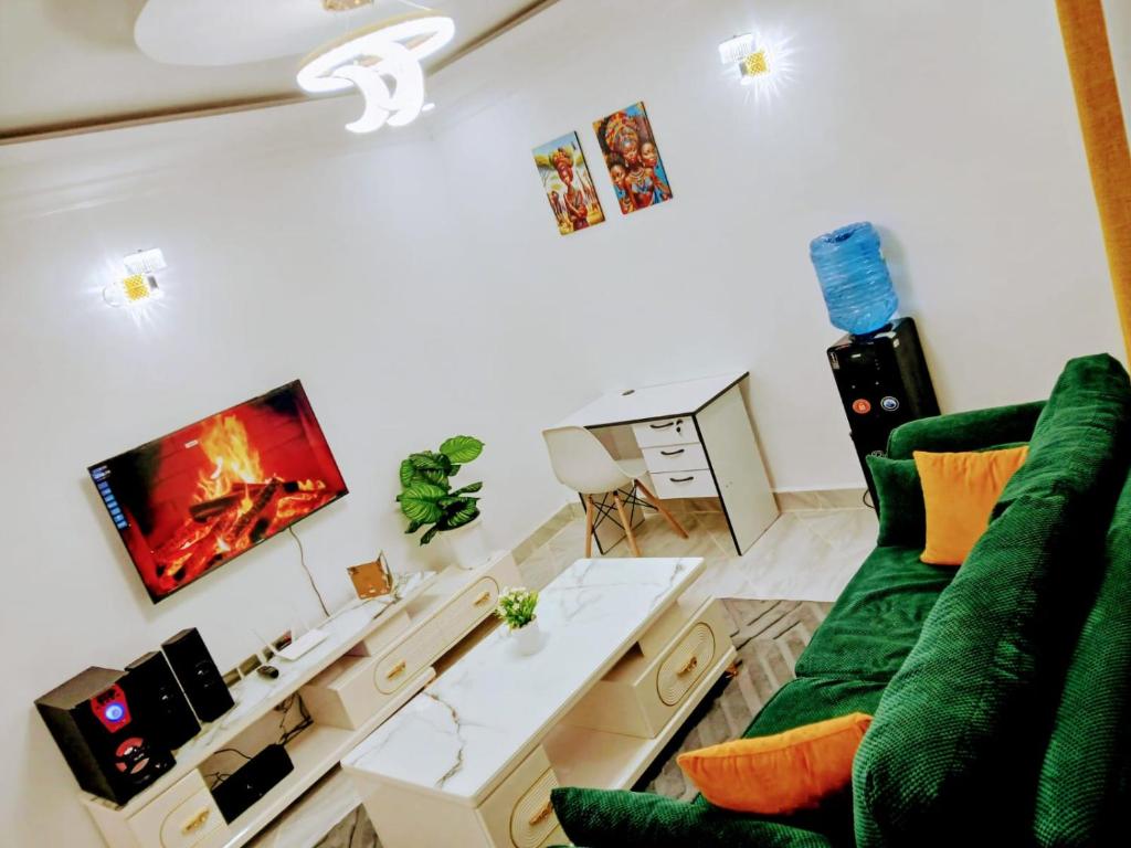 a living room with a green couch and a tv at Open Haven One Bedroom Apartments in Ongata Rongai 