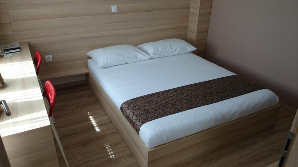 a small bed in a small room with a red chair at Postojna Rooms in Postojna