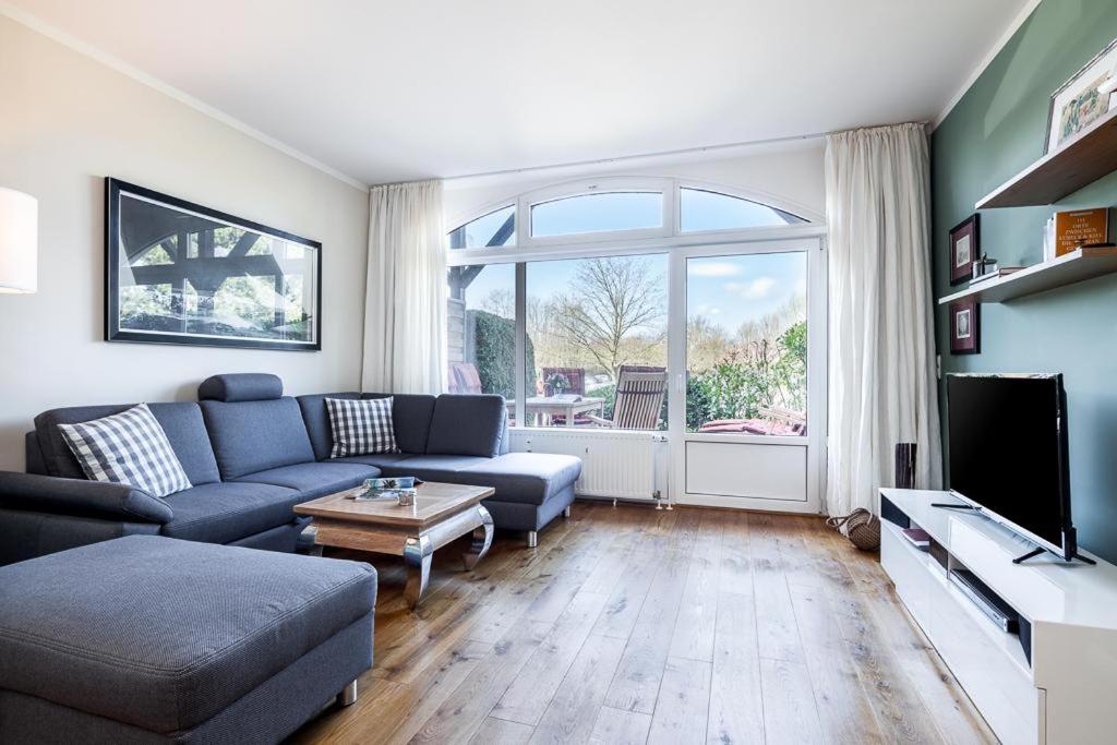 a living room with a blue couch and a large window at Golfresidenz B 002 in Grömitz