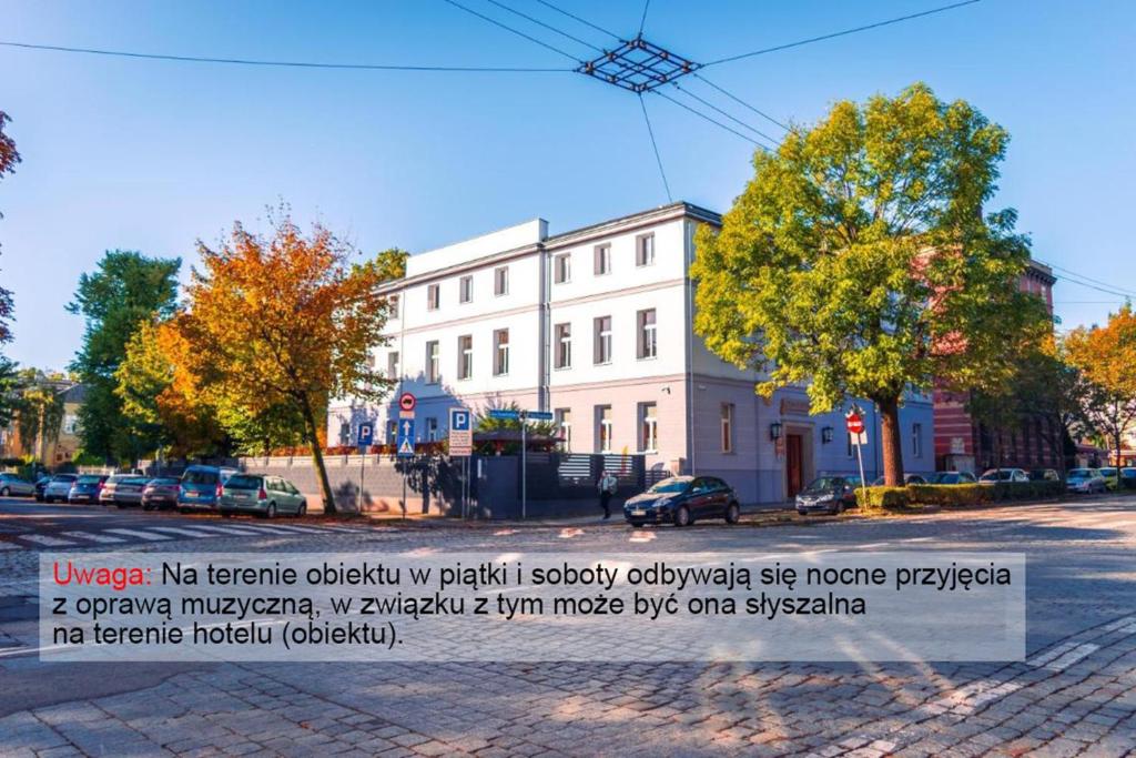 a white building with a sign in front of it at Sztuka Smaku - Restauracja i Hotelik in Świdnica