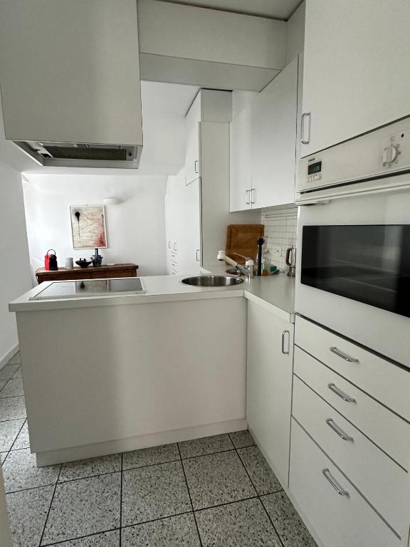 a white kitchen with white cabinets and a sink at Ferienhaus in Piazzogna in Gambarogno