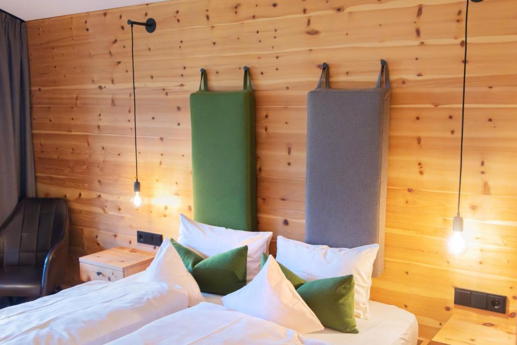 a bedroom with wooden walls and a bed with pillows at Hotel Alpenblick in Ohlstadt