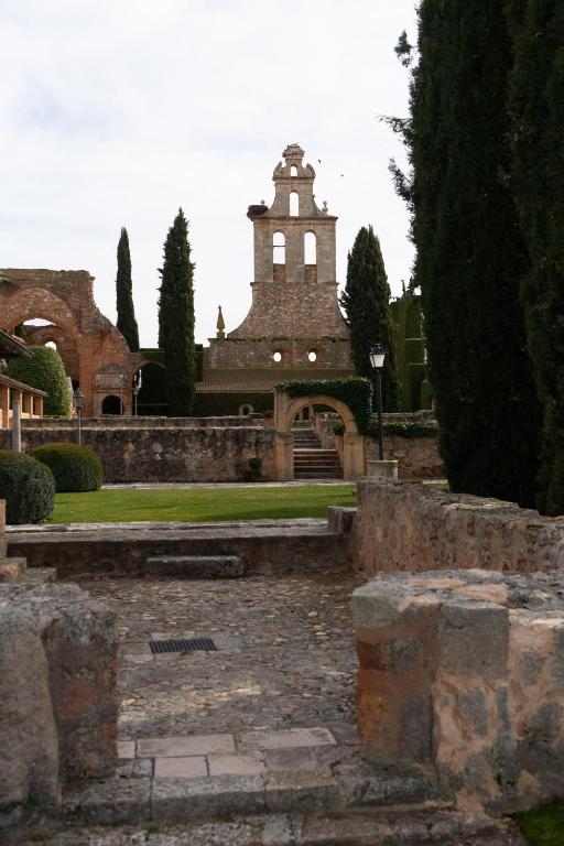 a building with a clock tower in a park at Los Claustros de Ayllón in Ayllón