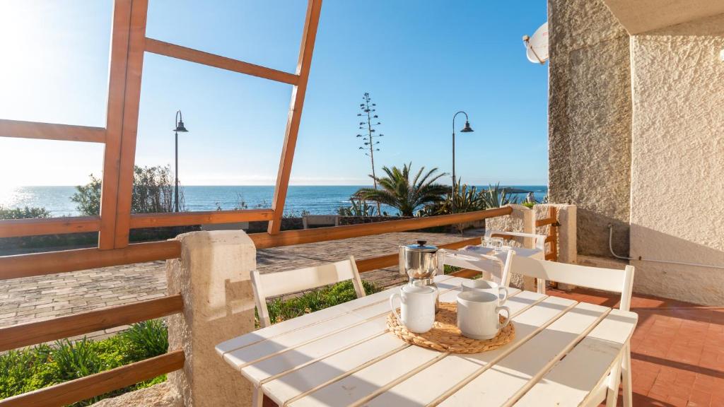 a table and chairs on a balcony with the beach at S'Archittu Sunset House in S'archittu Cuglieri