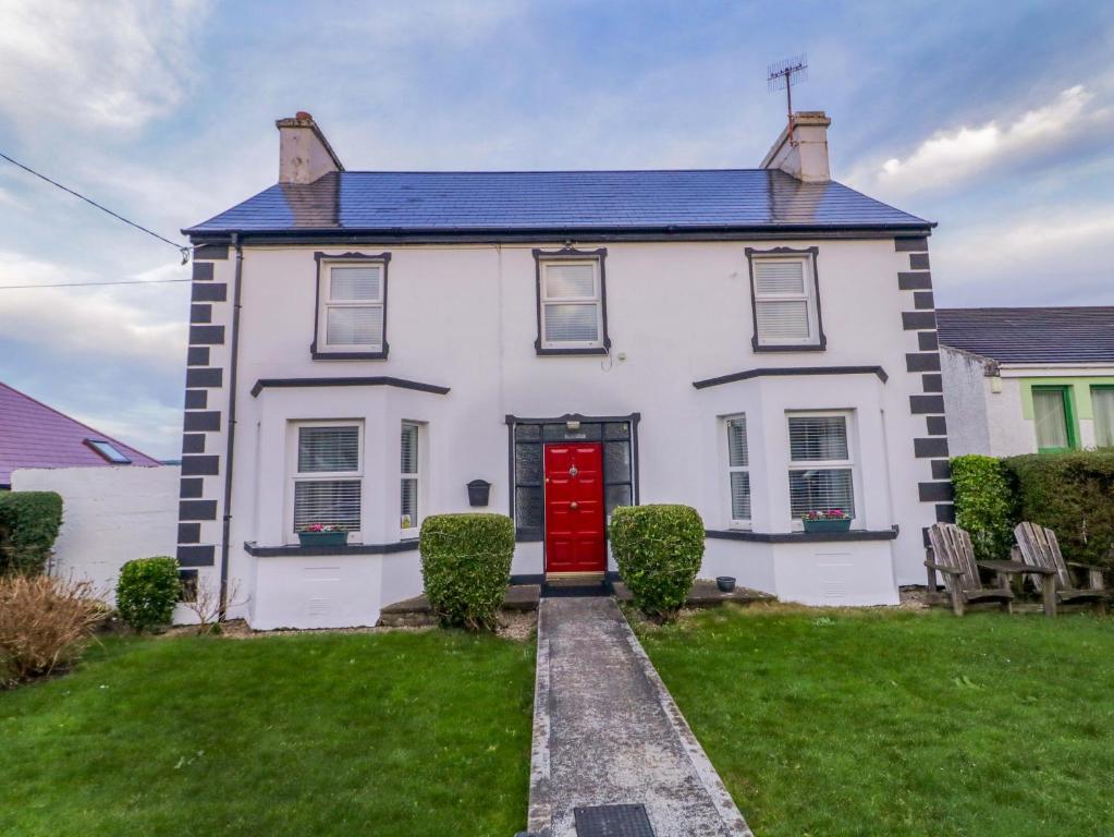 a white house with a red door and a yard at San Antonio in Dungloe