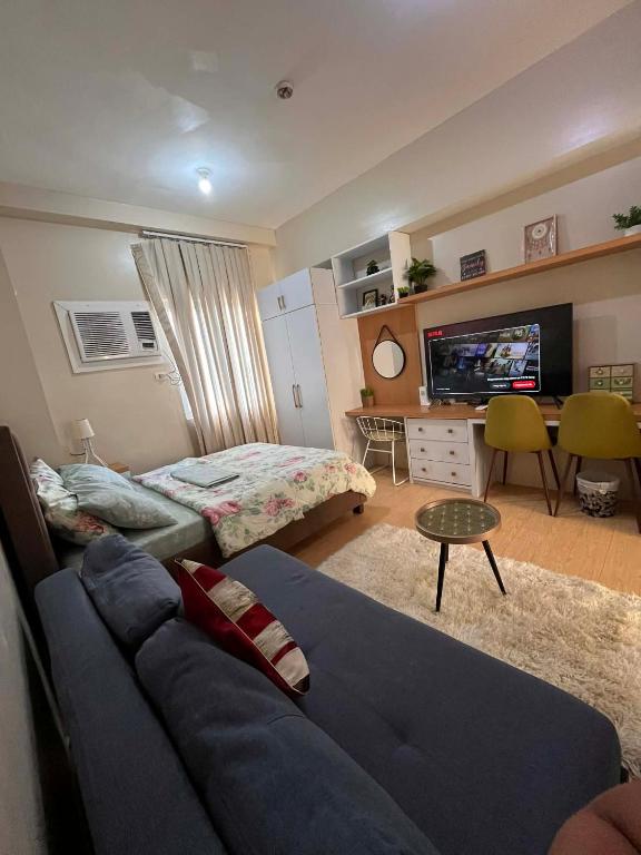 a living room with a blue couch and a bed at Sunvida Tower - Cebu Stay Rental in Dita