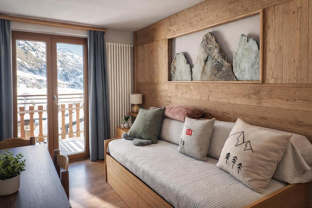 a bedroom with a couch with pillows and a balcony at Appartamento Alta Valle Maira - Provenzale in Villaro