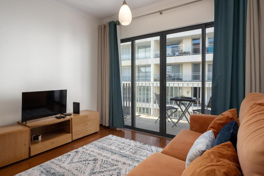 a living room with a couch and a television at Camélia's Apartment I by An Island Apart, Lda in Funchal