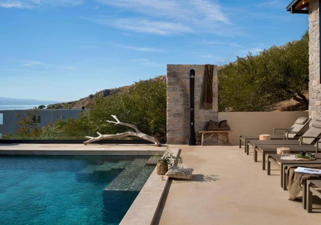 a swimming pool with chairs and a view of the ocean at Luxauthentic villa with heated pool SALT STONE - sauna, jacuzzi, gym, outdoor kitchen with bbq in Mimice