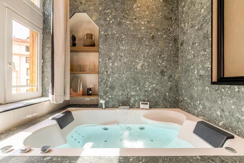 a bath tub in a room with a window at LaBolla, charmant cocon avec spa, cœur de Lyon in Lyon