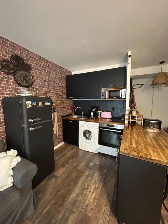 a kitchen with a black refrigerator and a stove at Studio loft city center in Tarnos