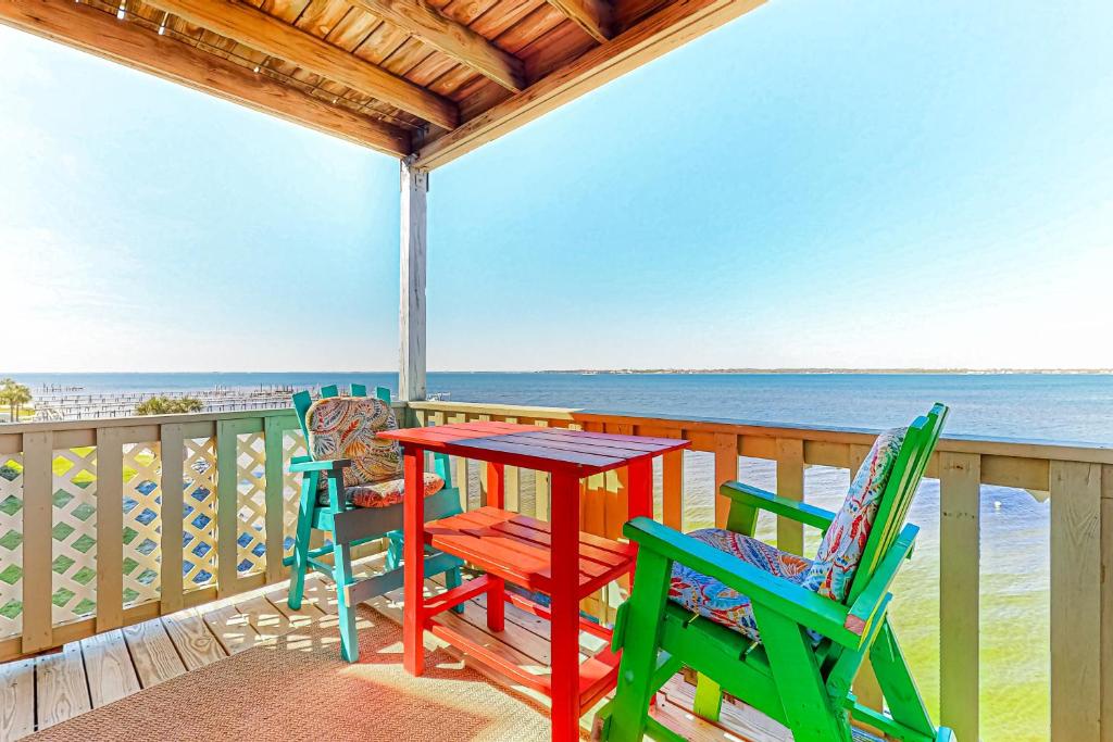 a table and chairs on a deck with the ocean at Third-floor beachfront condo with views washer&dryer heated pool in Pensacola Beach
