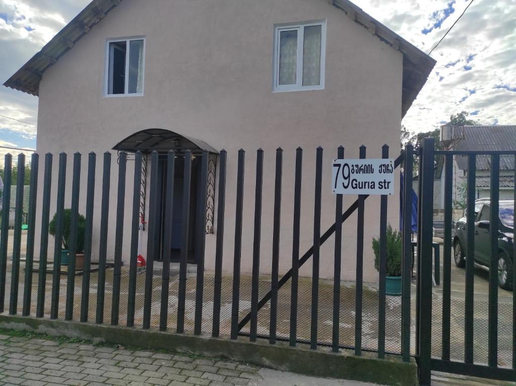 a house behind a fence with a sign on it at Guest house Family in Ureki