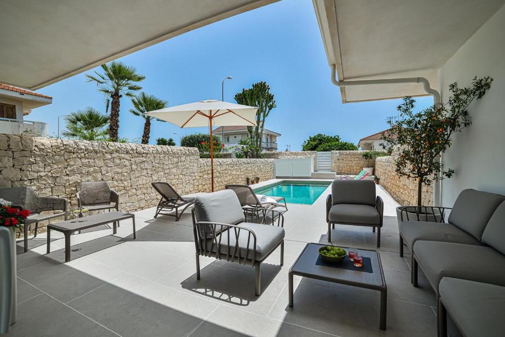 a patio with a couch and chairs and a pool at Villa Almaris in Marina di Ragusa