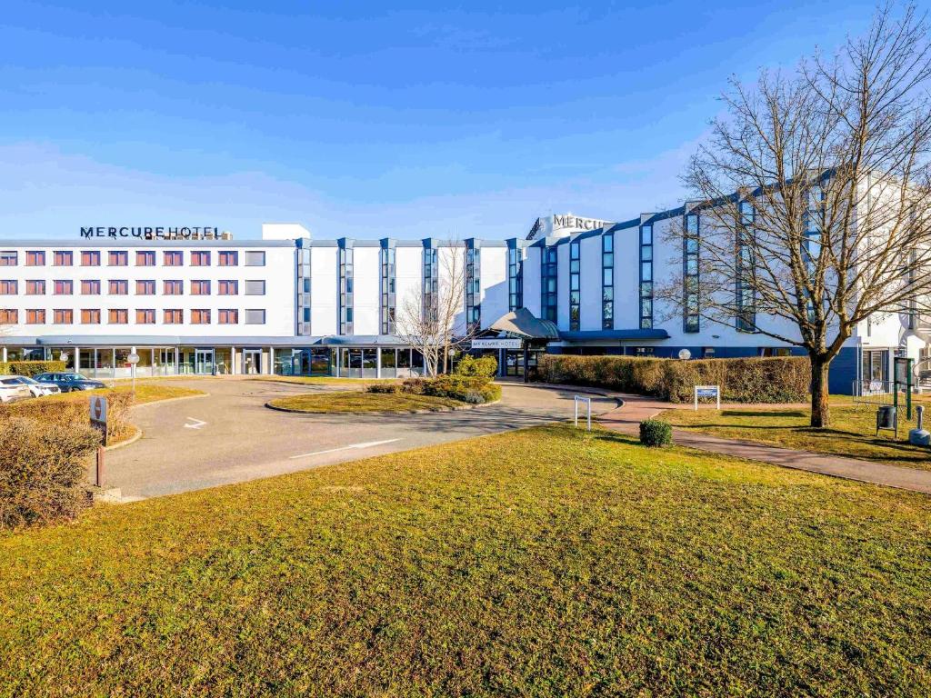 a large building with a parking lot in front of it at Mercure Lyon Est Villefontaine in Villefontaine