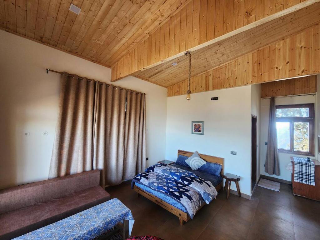 a bedroom with a bed and a couch and a window at Mangat Farm, Kanatal in Kanatal