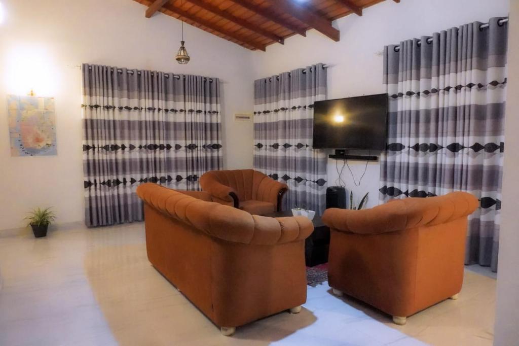 a living room with two chairs and a flat screen tv at Village Breeze Villa in Haputale