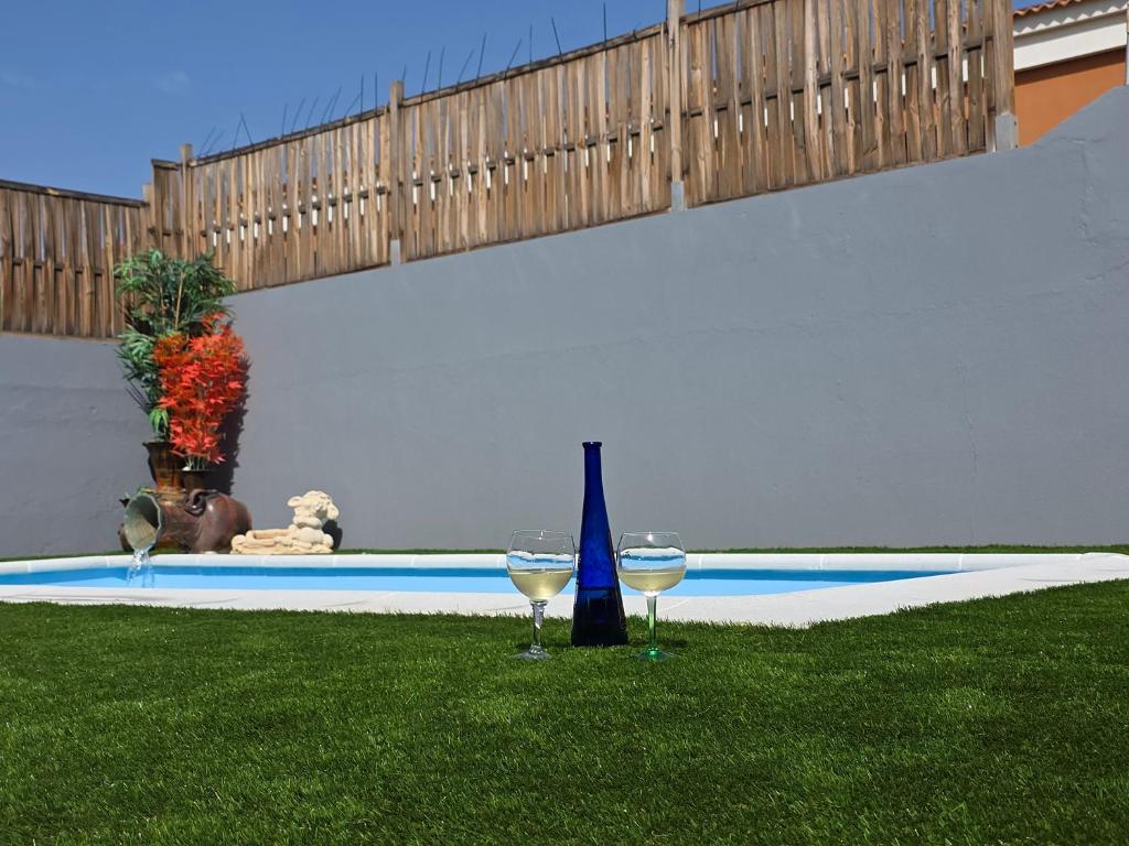 two glasses of wine sitting on the grass next to a pool at La Casa Sahi in Gáldar