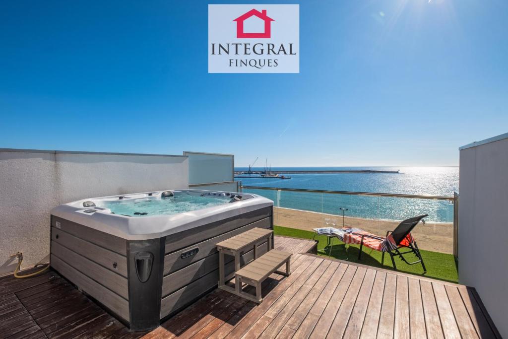 a hot tub on a deck with a table and a chair at Paradís Platja Apartment in Palamós