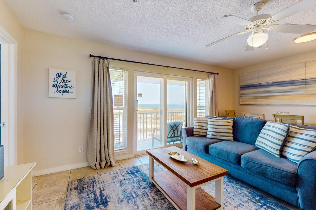 a living room with a blue couch and a table at Bright condo with shared pool beach access & central location in Navarre