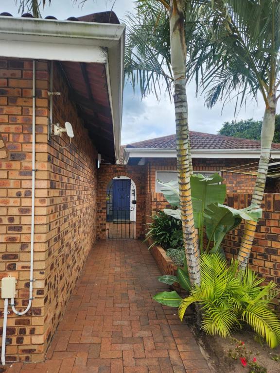 a brick building with a blue door and a palm tree at Ocean Sands Accommodation in Richards Bay