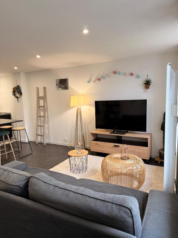 a living room with a couch and a flat screen tv at Granville appartement in Granville