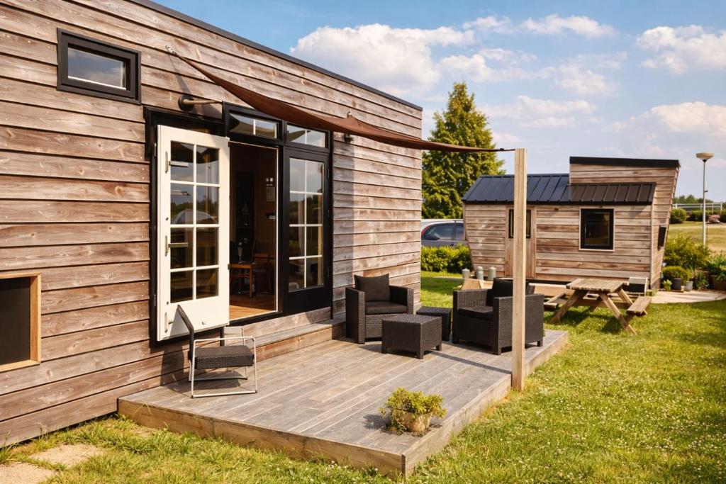 a tiny house with a deck next to a building at Tiny House in Heerewaarden