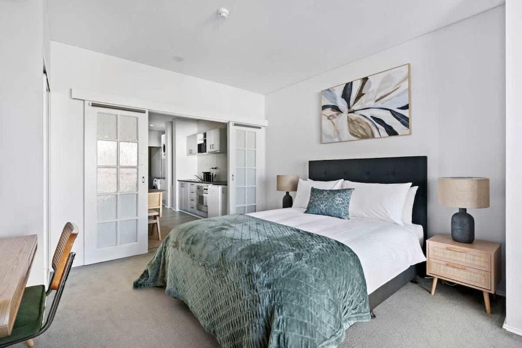 a white bedroom with a bed and a desk at Walk Everywhere - Large Apartment & Sofa Bed in Perth