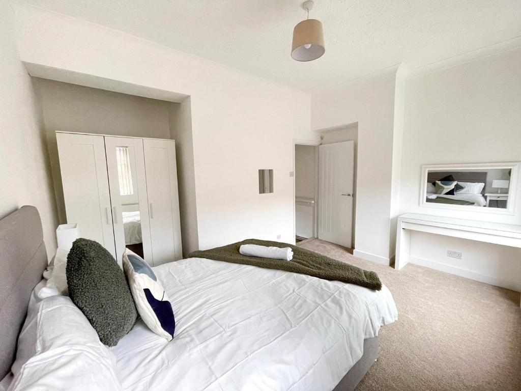 a bedroom with a large white bed with green pillows at 3 Bed plus Sofa sleeps 6 central in Middlesbrough