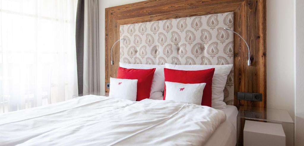 a white bed with red pillows in a bedroom at Dorfhaus Chalets in Oberstaufen