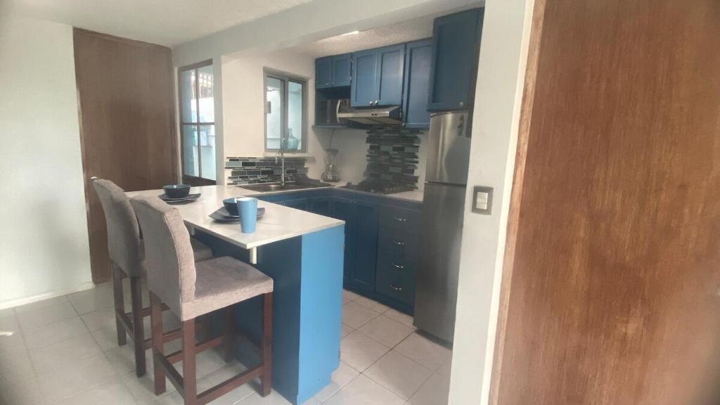 a kitchen with blue cabinets and a table and chairs at Casa pequeña in Acapulco